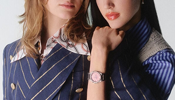 Two women modelling new-in Vivienne Westwood watches and jewellery in textured blue and brown outfits